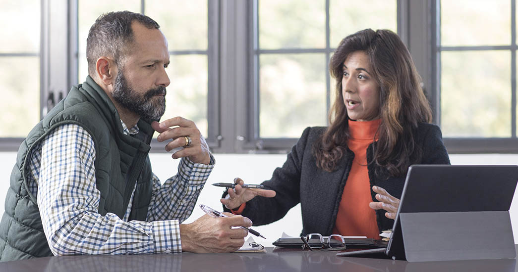 Two colleagues in a business meeting talking in a sunlit room