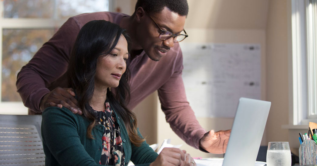 Employer talking to employee at their computer