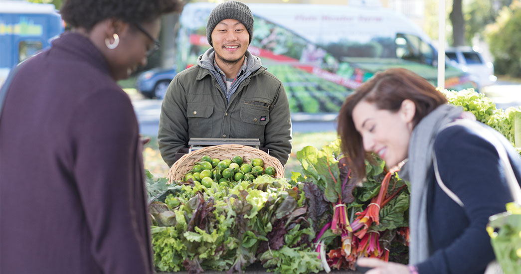 Three people shopping for lettuce at a farmer's market