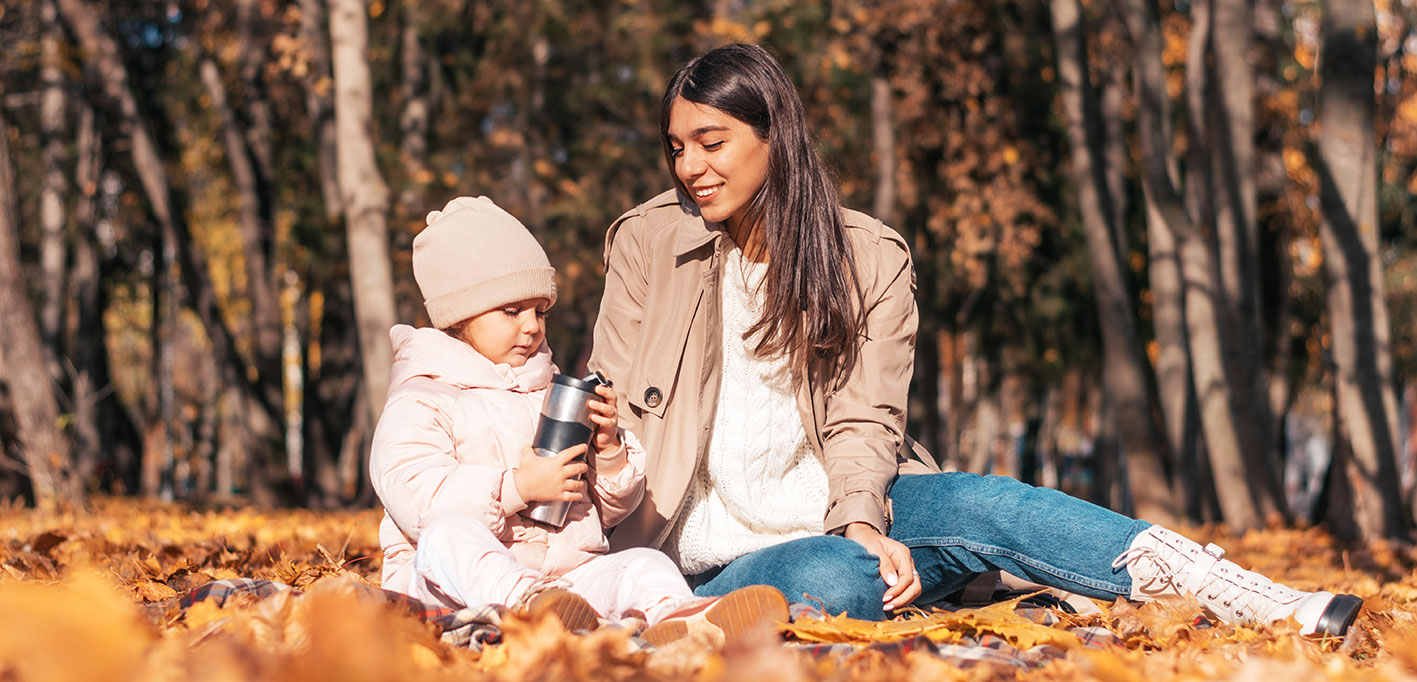 mom and daughter sitting outside in the autumn leaves